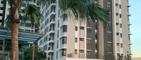 Un edificio moderno de gran altura con varios balcones y una pasarela techada.