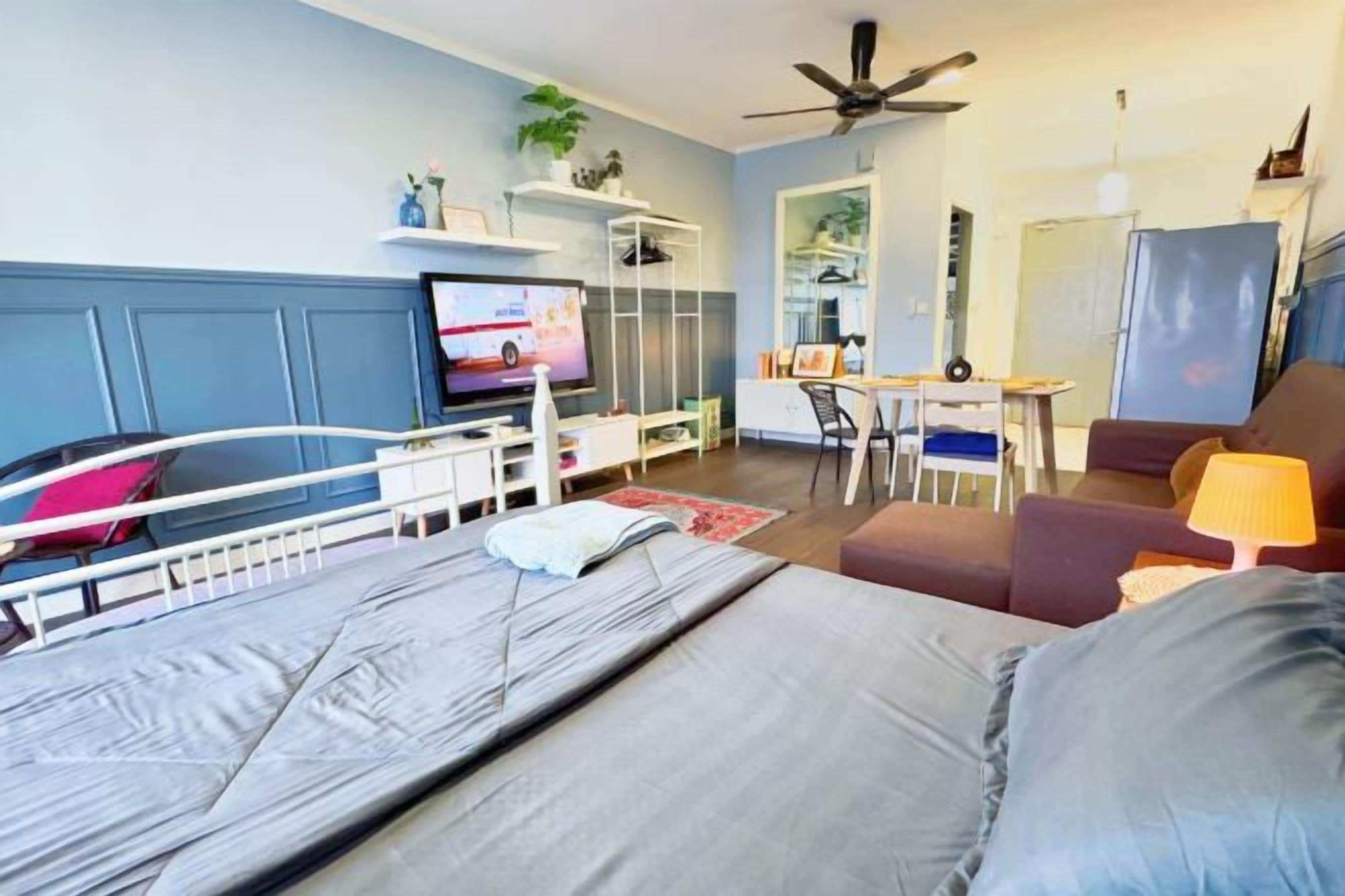 A hotel room with a bed, a desk, a chair, a TV, and a ceiling fan.