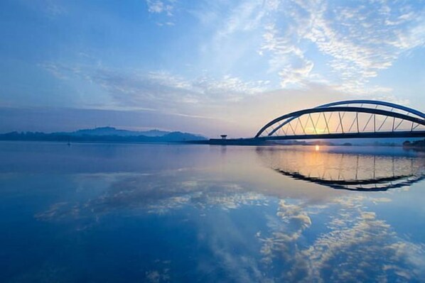 A bridge over a calm body of water with a clear sky and distant mountains. - Pool View Air-Con Studio @Tiara Imperio Bangi (Kajang)