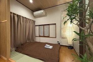 A room with a bed, an air conditioner, a plant, and a traditional Japanese shoji screen. - Nestay villa Tokyo Ueno (Tokyo)