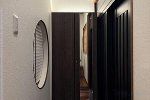 A hallway with a door, a light switch, and a wall-mounted mirror. - Nestay villa Tokyo Ueno (Tokyo)