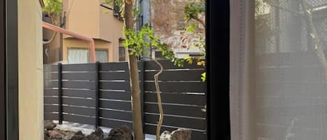 Vista de un patio con valla negra, un árbol y un muro de piedra.