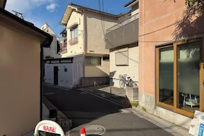 A narrow street with buildings on both sides, a bicycle parked by the sidewalk, and a visible entrance to a building. - Nestay villa Tokyo Ueno (Tokyo)