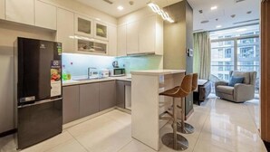 A modern kitchen with a refrigerator, microwave, and bar stools. - An Corner Apt - Vinhomes Central Park High Floor Nice View and Free Pick up for 5 Nights (Ho Chi Minh City)