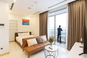 A modern hotel room with a bed, sofa, and a balcony with a view. - An Corner Apt - Vinhomes Central Park High Floor Nice View and Free Pick up for 5 Nights (Ho Chi Minh City)