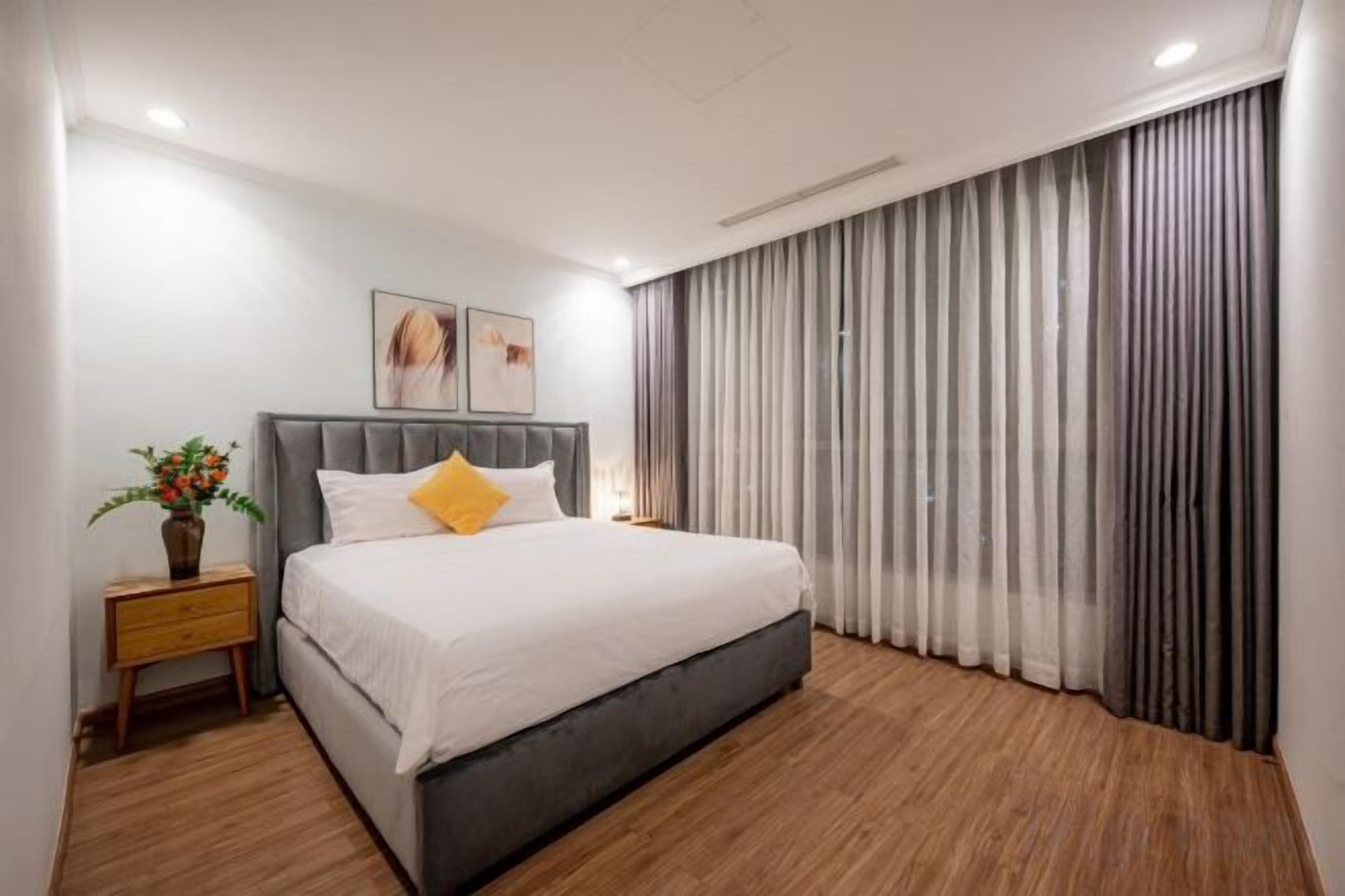 A modern bedroom with a large bed, a nightstand, and a potted plant.