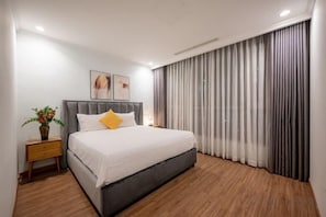 A modern bedroom with a large bed, a nightstand, and a potted plant. - An Corner Apt - Vinhomes Central Park High Floor Nice View and Free Pick up for 5 Nights (Ho Chi Minh City)