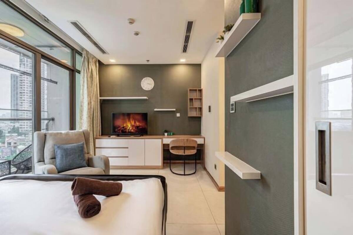 Ein modernes Hotelzimmer mit Bett, Schreibtisch, Fernseher und einem Balkon mit Blick auf die Stadt.