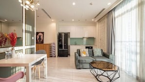 A modern living room with a dining area, a sofa, and a coffee table. - An Corner Apt - Vinhomes Central Park High Floor Nice View and Free Pick up for 5 Nights (Ho Chi Minh City)