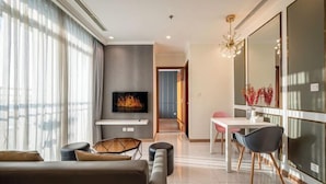 A modern living room with a fireplace, a dining area, and a large mirror. - An Corner Apt - Vinhomes Central Park High Floor Nice View and Free Pick up for 5 Nights (Ho Chi Minh City)