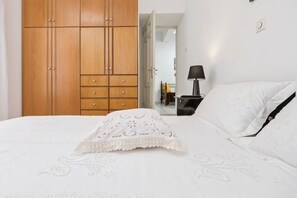 A bedroom with a bed, a nightstand, a lamp, a wardrobe, and a mirror. - Akakia Residence (Naxos)