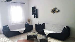 A living room with two black sofas, a coffee table, and a wall-mounted shelf. - Akakia Residence (Naxos)