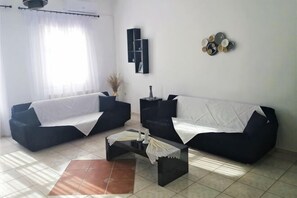 A living room with two black sofas, a coffee table, and a wall-mounted shelf. - Akakia Residence (Naxos)