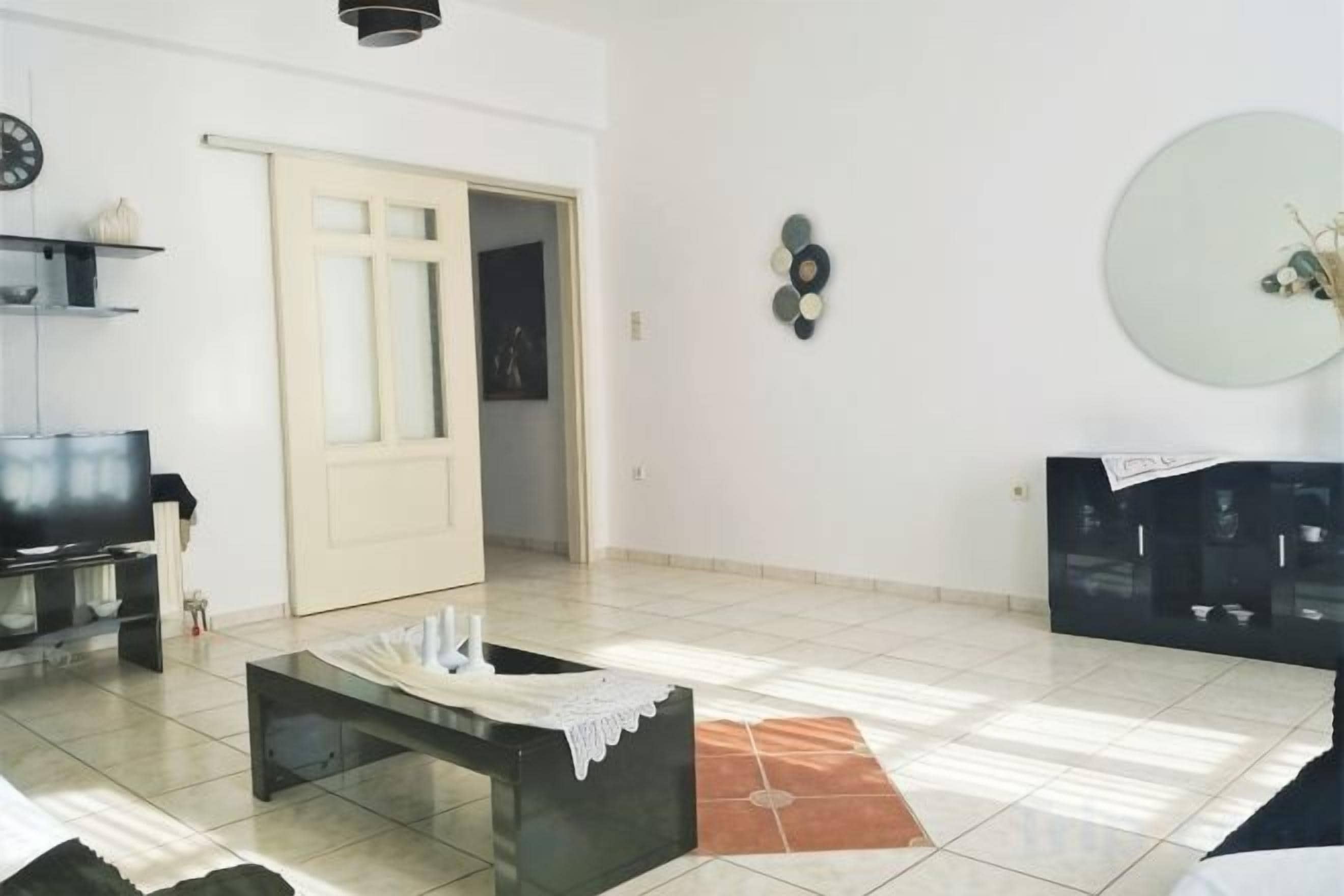 Un salon comprenant un canapé, une table basse, un téléviseur et une porte donnant sur une autre pièce.