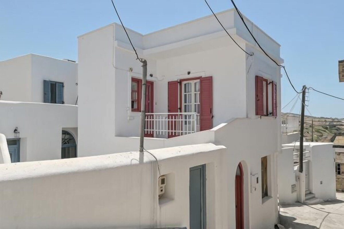 A white building with red shutters and a balcony.