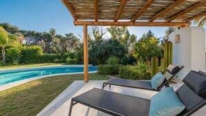 Zona de piscina con sillas de descanso y una pérgola.