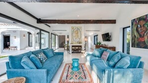 Ein geräumiges Wohnzimmer mit zwei blauen Sofas, einem Couchtisch und einem Kamin.