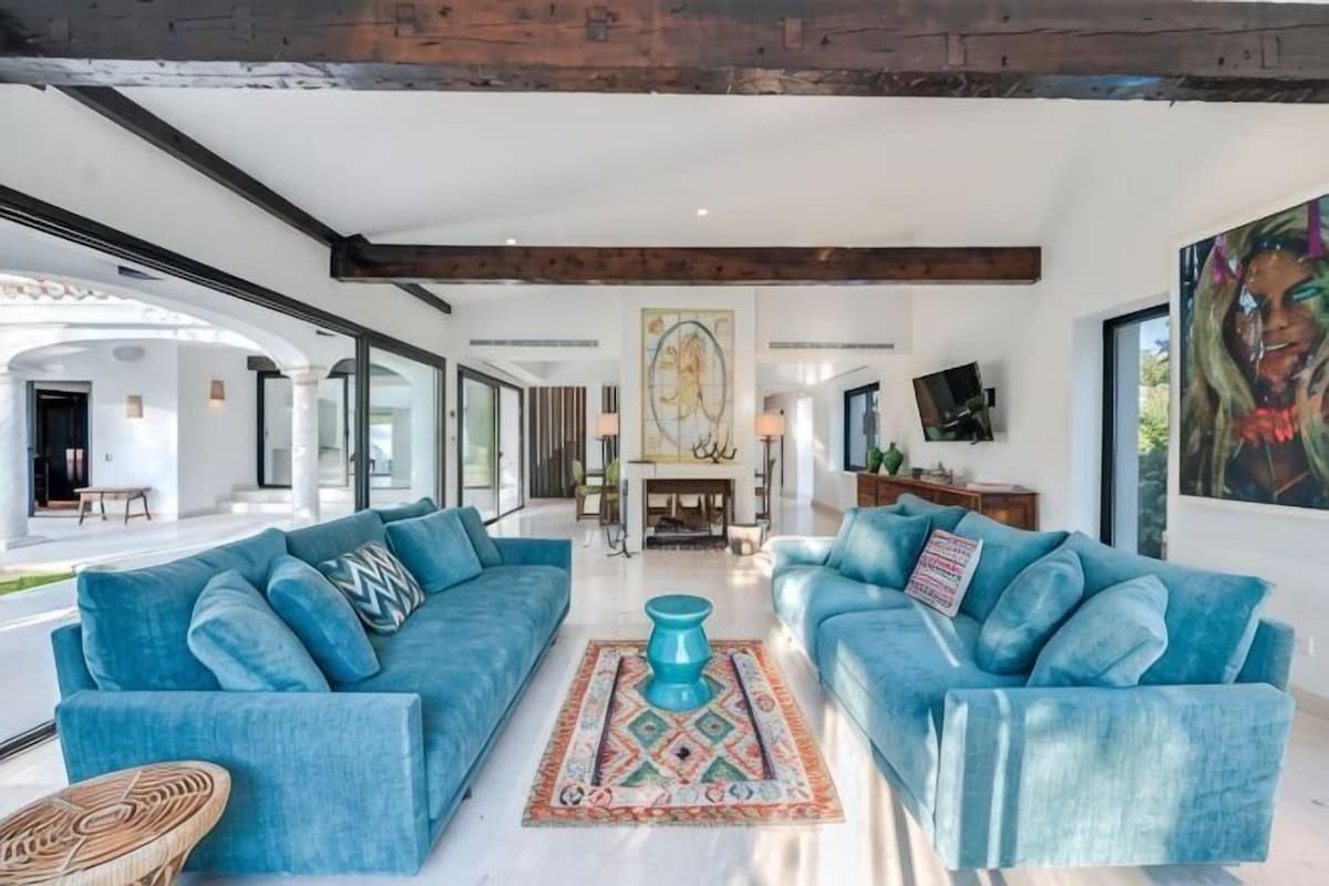 Un salón espacioso con dos sofás azules, una mesa de centro y una chimenea.