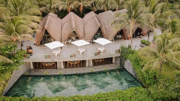 A resort with a pool, thatched-roof structures, and lush greenery. - Nhà Nguyên Căn Costis 5 Phòng Ngủ (Phu Quoc Island)