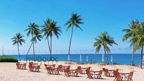A beachside restaurant with outdoor seating, palm trees, and a view of the ocean. - Nhà Nguyên Căn Costis 5 Phòng Ngủ (Phu Quoc Island)