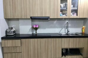 Una cocina con armarios de madera, encimera negra, pileta de acero inoxidable y un pequeño florero con flores.
