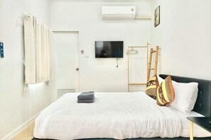 A hotel room with a bed, a television, an air conditioning unit, and a door. - Cina Home (Chiang Mai)