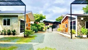 A courtyard with buildings, gravel path, and potted plants. - Cina Home (Chiang Mai)