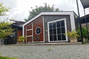 A modern building with a large window, a bench, and a circular design element. - Cina Home (Chiang Mai)