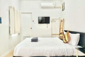 A hotel room with a bed, a TV, a wardrobe, and a window. - Cina Home (Chiang Mai)