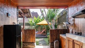 A compact kitchen with a refrigerator, wooden cabinets, and a small sink. - Villa Lestaru Ubud (Bali)