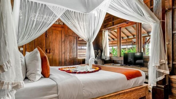 A bed with a canopy, wooden walls, and a television in a room. - Villa Lestaru Ubud (Bali)