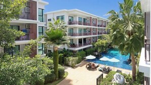 A modern hotel with a rooftop pool, lush greenery, and multiple balconies. - Rawai Beach Pool Condotel (Phuket)