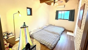 Un dormitorio con cama, mesita de noche, lámpara, silla y ventana.