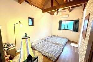 Een slaapkamer met een bed, nachtkastje, lamp, stoel en raam.