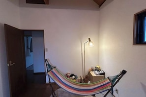 A hammock in a room with a standing lamp and a small table with items on it.