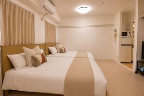 A hotel room with two beds, a microwave, and a television.