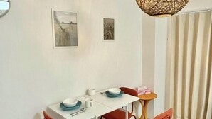 A dining area with a white table, red chairs, and two framed pictures on the wall. - YMK Oshiage 5B (Tokyo)