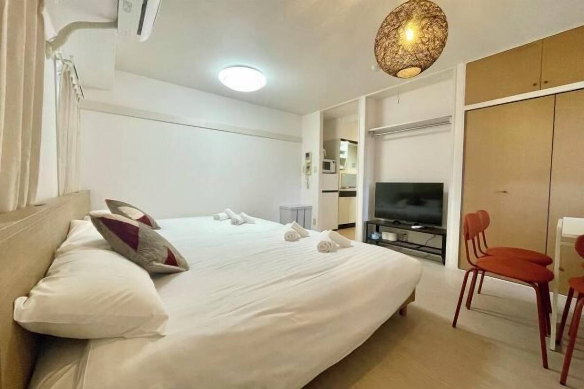 Una habitación de hotel con una cama, televisión, armario y una silla.