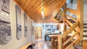 Un interior espacioso con escalera de madera, zona de cocina y comedor.
