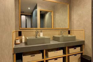Une salle de bain avec deux lavabos, un miroir et des paniers de rangement.