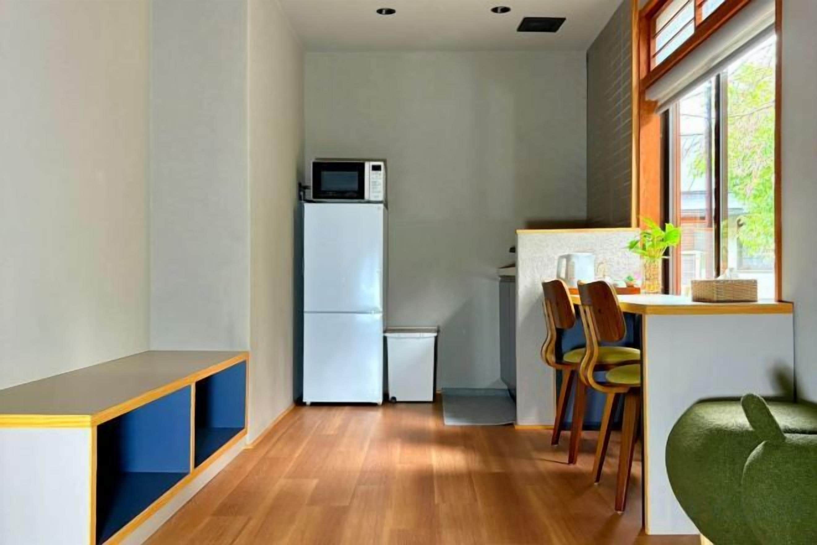 A compact kitchen with a microwave, refrigerator, and a small dining area with chairs.