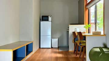 A compact kitchen with a microwave, refrigerator, and a small dining area with chairs.