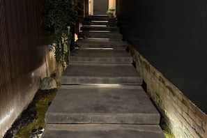 A series of concrete steps leading up to a door, surrounded by a dark wall and some greenery. - SOSEI-IN@YASAKA TEMPLE (Kyoto)