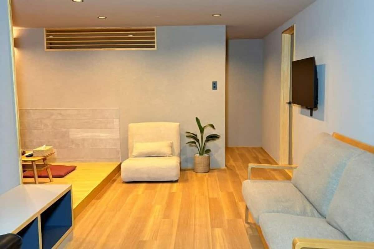 A modern living room with a sofa, a chair, a small table, and a potted plant.