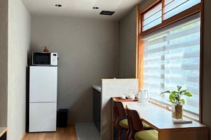 A compact kitchen with a refrigerator, microwave, and a small dining area with a table and chairs. - SOSEI-IN@YASAKA TEMPLE (Kyoto)