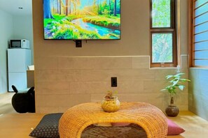 A room with a television mounted on the wall, a wicker table with a vase, and a potted plant. - SOSEI-IN@YASAKA TEMPLE (Kyoto)