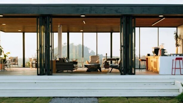 A modern outdoor seating area with a mix of chairs and sofas, a small table, and a grill.