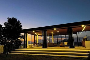 A modern building with large glass windows, a flat roof, and a spacious outdoor area with seating. - Akano Doichang (Mae Suai)