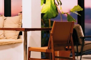 A chair with a cushioned seat and backrest, positioned in a room with a view of a plant and a window. - Akano Doichang (Mae Suai)