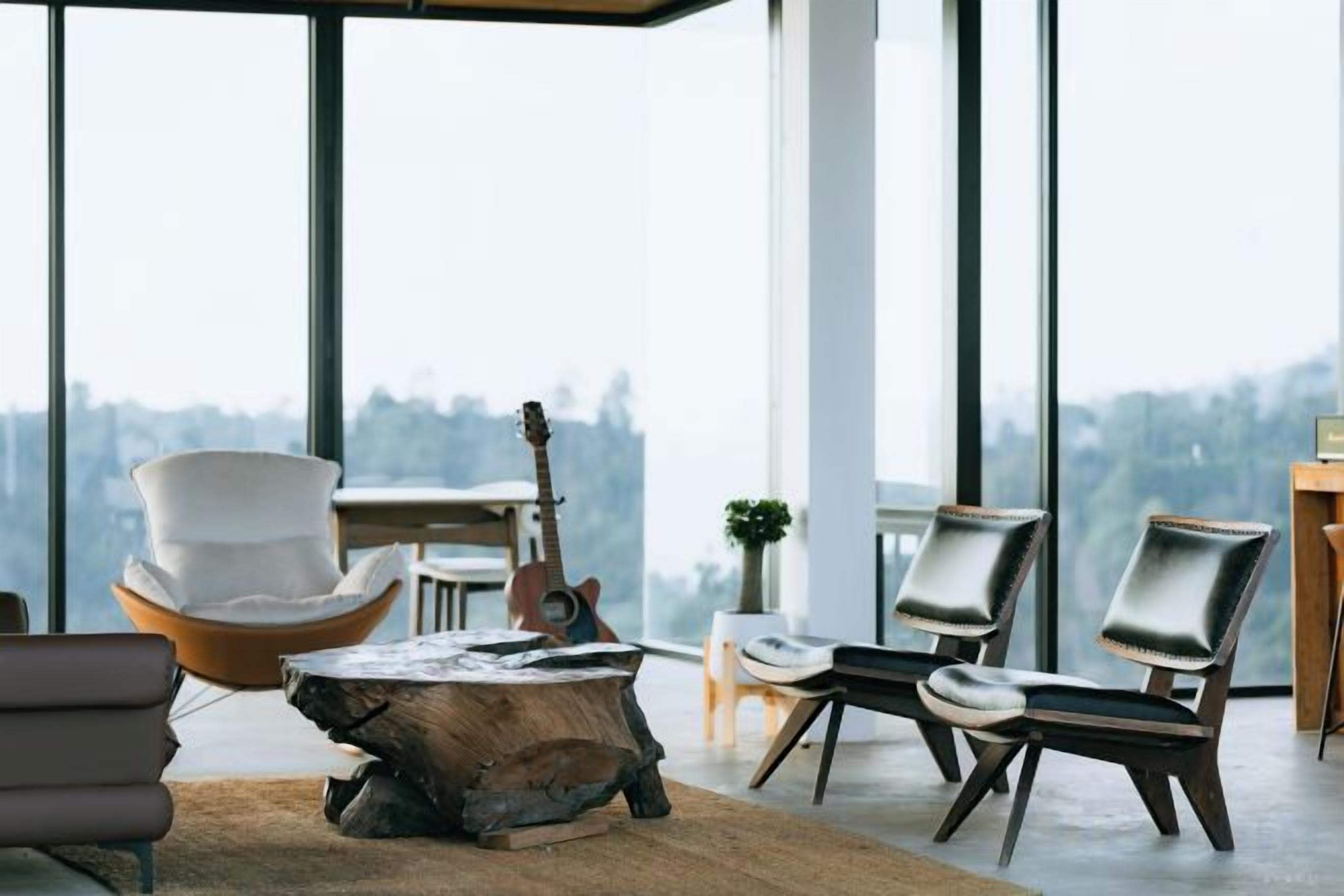 A modern living room with a large window, a wooden coffee table, and two leather chairs.